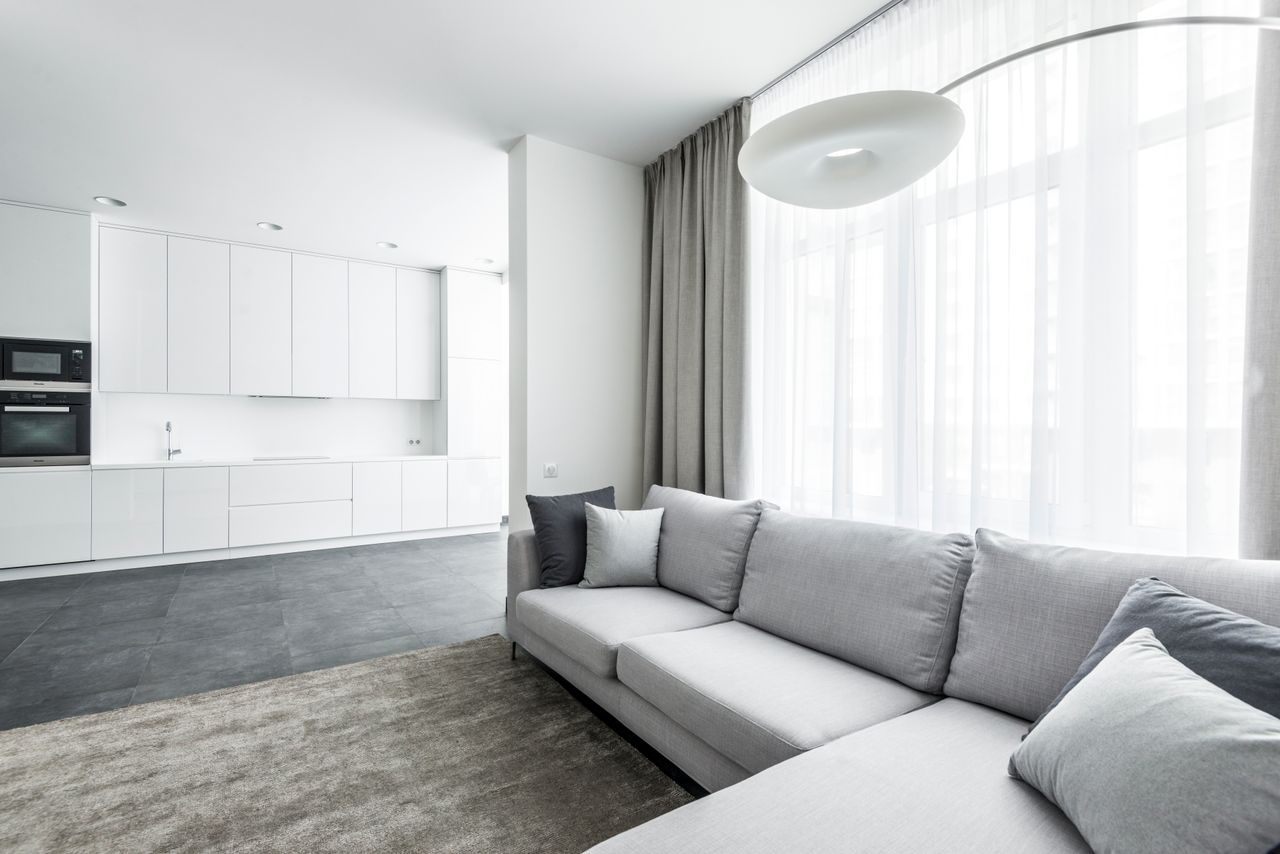 gallery-02 Bright modern living area featuring a cozy sofa and minimalist kitchen background.